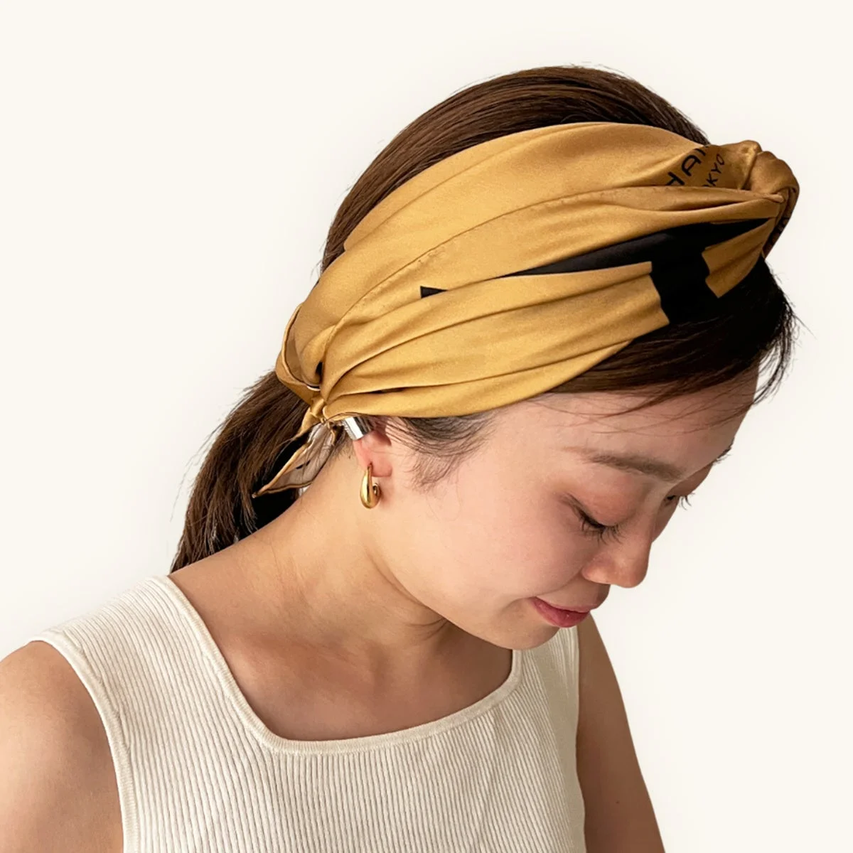 ゴールドのヘアスカーフでヘアアレンジをした女性の横顔