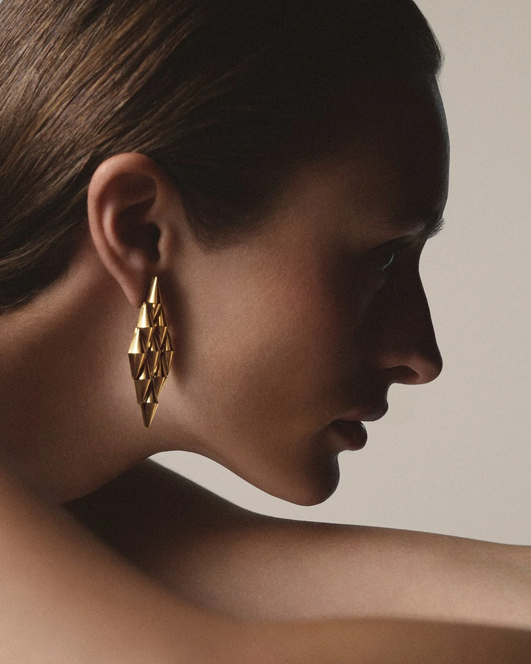 女性の横顔と幾何学的なゴールドイヤリング