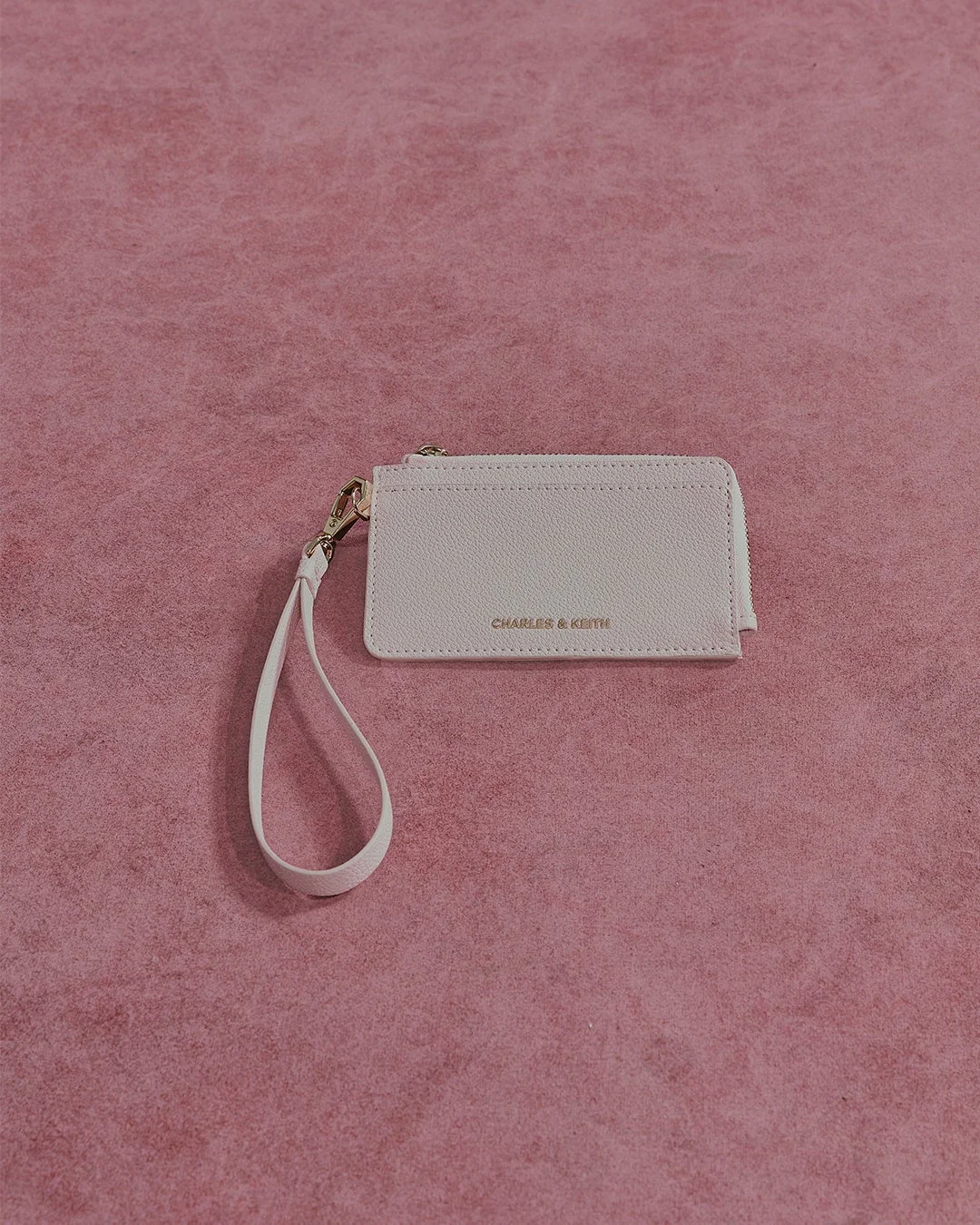 CHARLES & KEITHのロゴが入った淡いピンク色のミニウォレットまたはカードケース