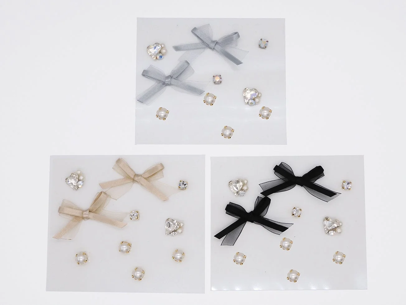 グレー、ベージュ、ブラックの3色のリボンと、パール、ラインストーンがセットになったデコレーションパーツが写っています。ハンドメイドやネイルアートなどに使える素材です。