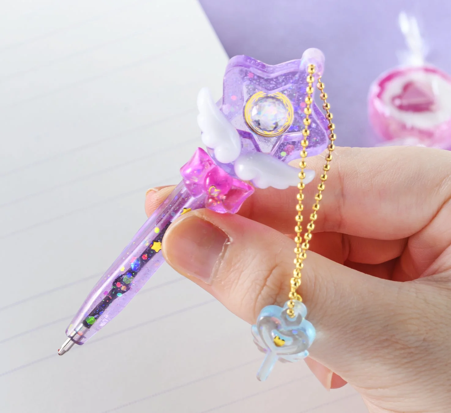 星と羽根の飾りがついた紫色のキラキラペン